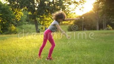 小女孩在绿色的草地上玩，同时做一个杂技轮。 年轻的运动小子有一个非常好的心情。